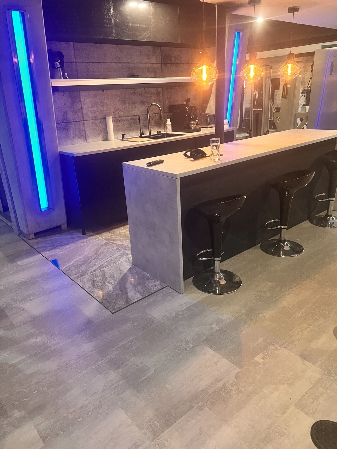 Residential home bar with blue integrated accent lighting and warm pendant lights